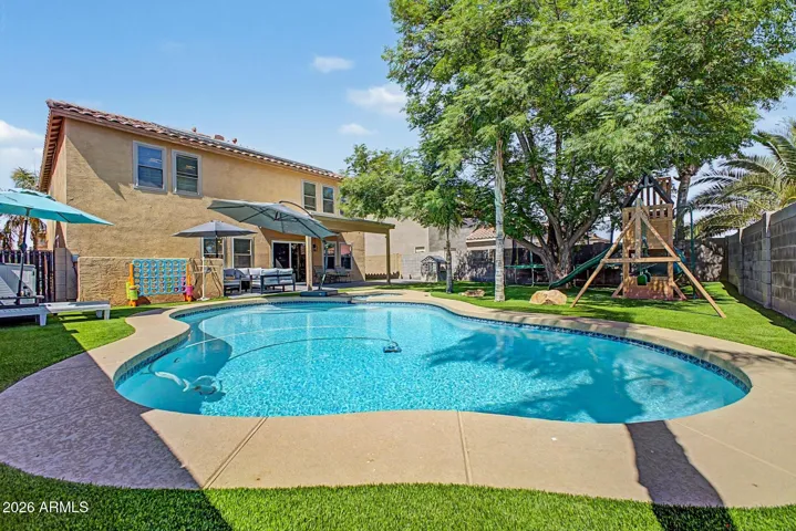 Resort-style pool surrounded by lush landscaping and mature shade trees.