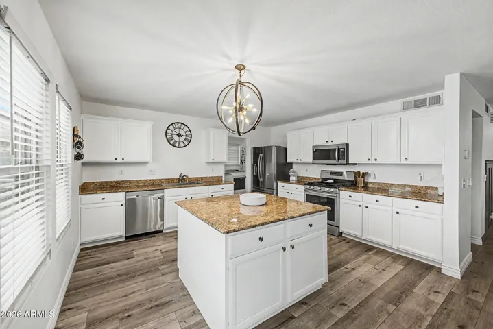 Bright kitchen featuring painted cabinetry, granite countertops, stainless appliances, and large island.