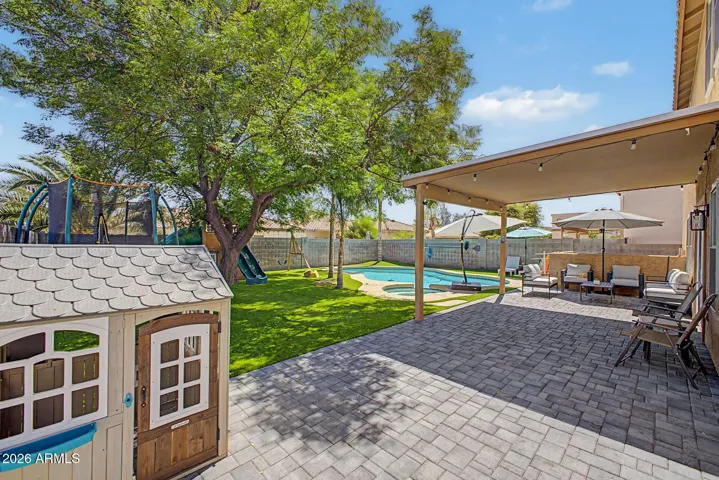 Beautifully landscaped backyard featuring pool, spa, pavers, and artificial turf.