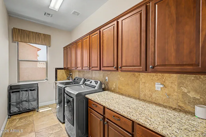 Laundry room offers an abundant workspace & storage, featuring extensive cabinetry & generous counter spaces