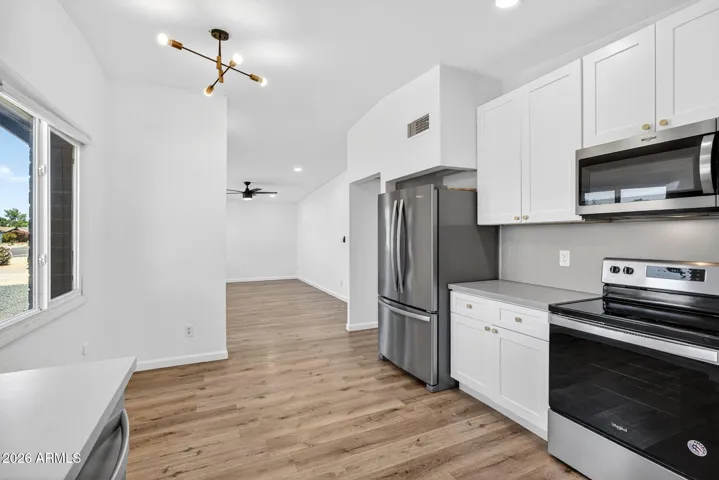 Spacious living room, neutral LVP flooring throughout, matte black fixtures, recessed lighting, stainless steel appliances.