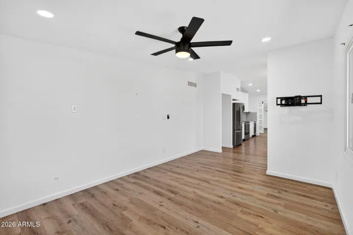 Spacious living room, neutral LVP flooring throughout, matte black fixtures, recessed lighting, stainless steel appliances.