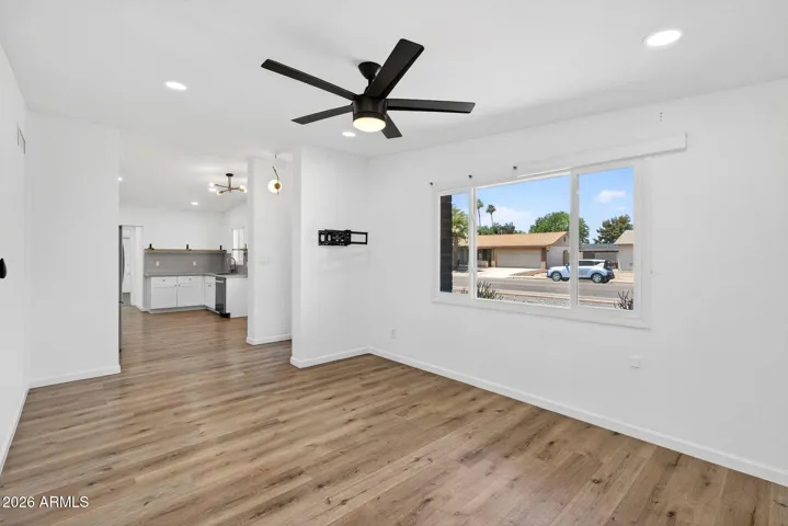 Spacious living room, neutral LVP flooring throughout, matte black fixtures, stainless steel appliances.