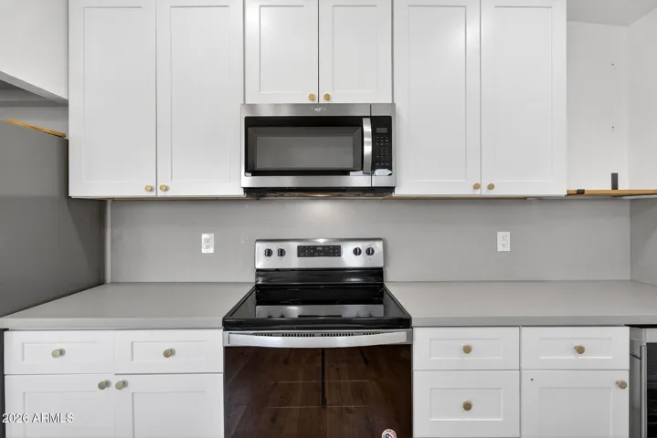 Spacious living room, neutral LVP flooring throughout, matte black fixtures, recessed lighting, stainless steel appliances.