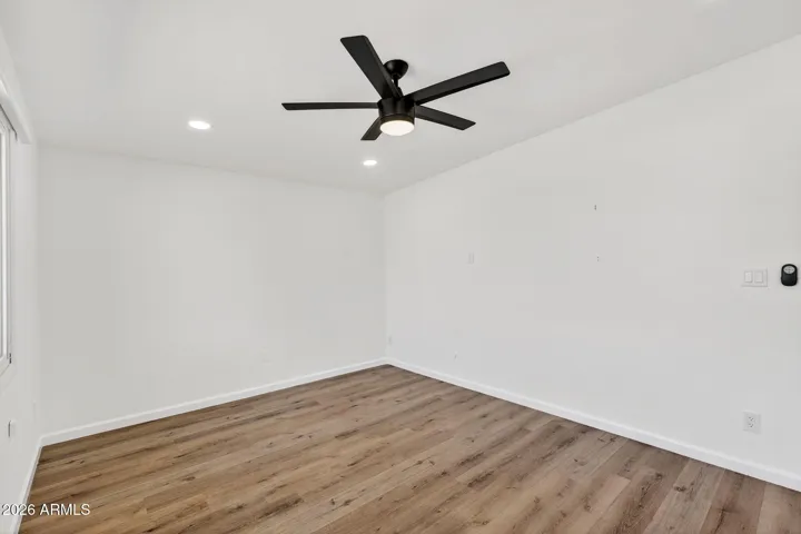 Spacious living room, neutral LVP flooring throughout, matte black fixtures, recessed lighting, stainless steel appliances.