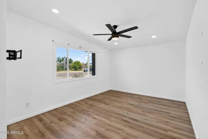 Spacious living room, neutral LVP flooring throughout, matte black fixtures, recessed lighting, stainless steel appliances.