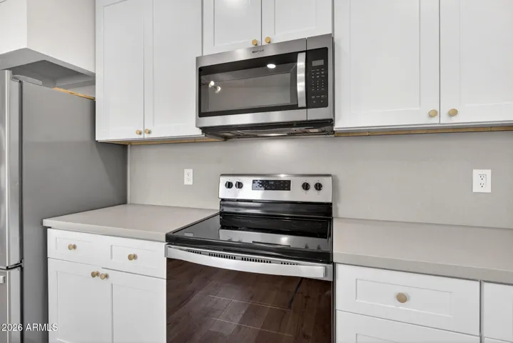 Spacious living room, neutral LVP flooring throughout, matte black fixtures, recessed lighting, stainless steel appliances.