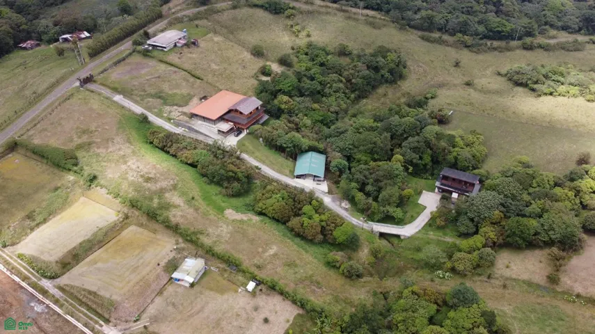 Aerial view of the property featuring two mountain-style cabins, private equestrian training arena, and over 18 hectares surrounded by nature near Braulio Carrillo National Park.