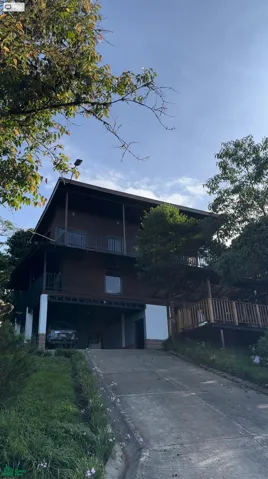 Three-level mountain-style residence featuring expansive terraces, covered parking, and elegant wood finishes surrounded by lush natural scenery.