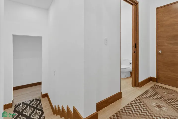 stairs leading down to 1 bedroom apartment and hallway entering into half bath and cinema room