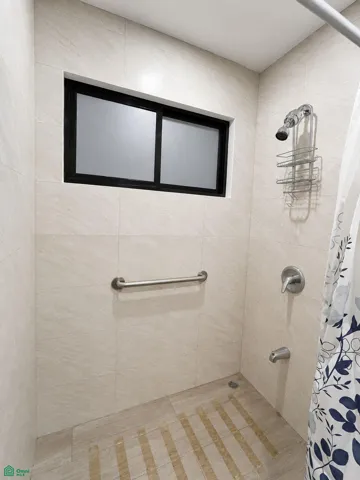 Tiled shower with a frosted window and convenient safety grab bar.
