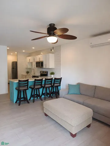 Bright open-plan living area and kitchen with breakfast-bar seating.