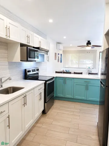 Modern kitchen with appliances, light countertops and ample cabinetry.