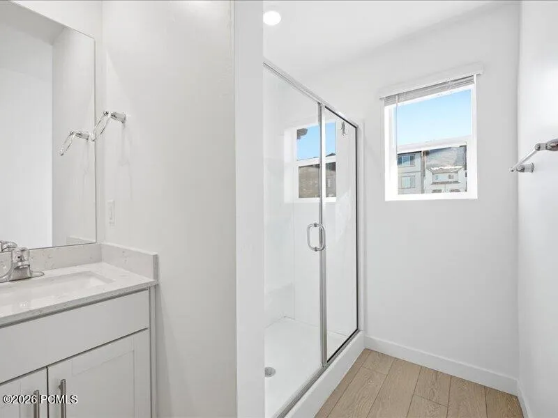 Primary en-suite bathroom with double vanity, a shower stall, and water closet