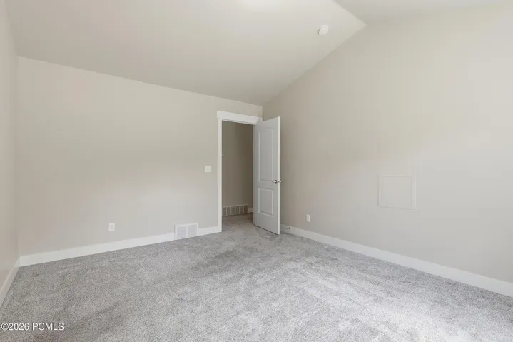 Spacious and light master suite featuring vaulted ceilings and neutral wall tones.