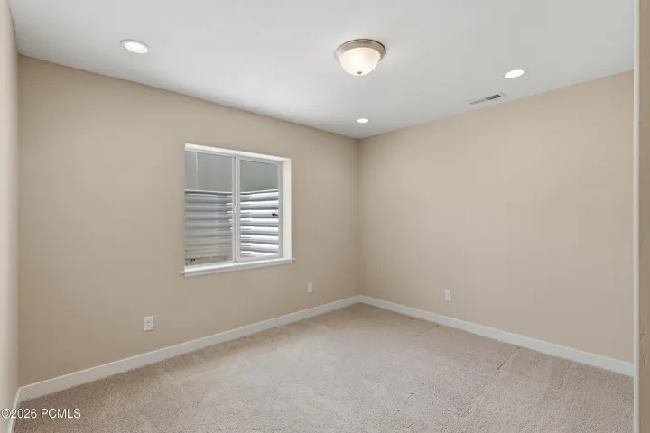 Spacious and light bedroom #4 with a large window and recessed and flush-mount lighting.