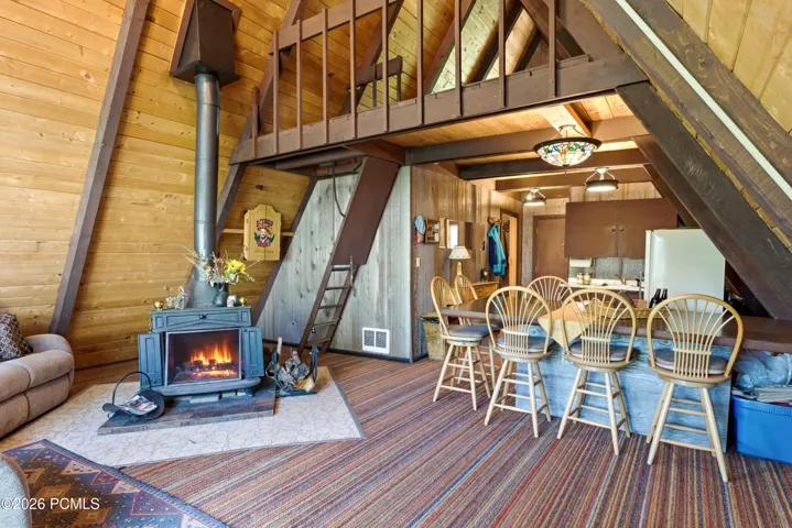 Spacious A-frame cabin open-plan living and dining area with wood-burning stove, loft above in Timberlake, Utah