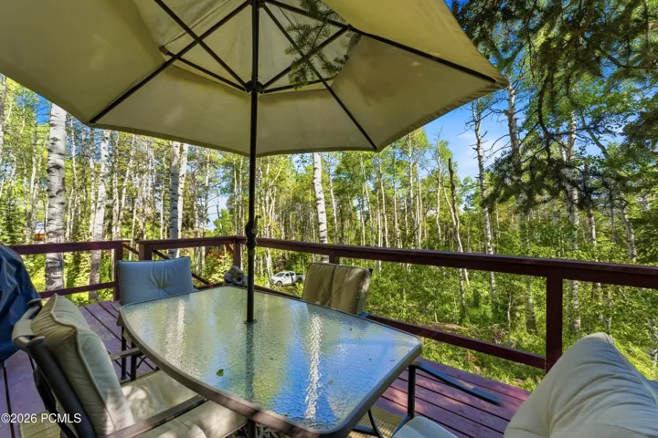 Private cabin deck with patio dining table, umbrella, and scenic wooded view in Timberlake, Utah