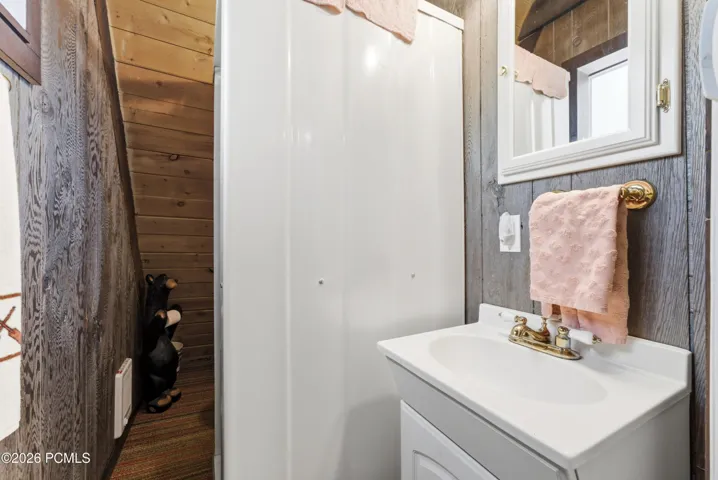 Cabin bathroom with stand-up shower, white vanity sink, and rustic wood accent wall in Timberlake, Utah