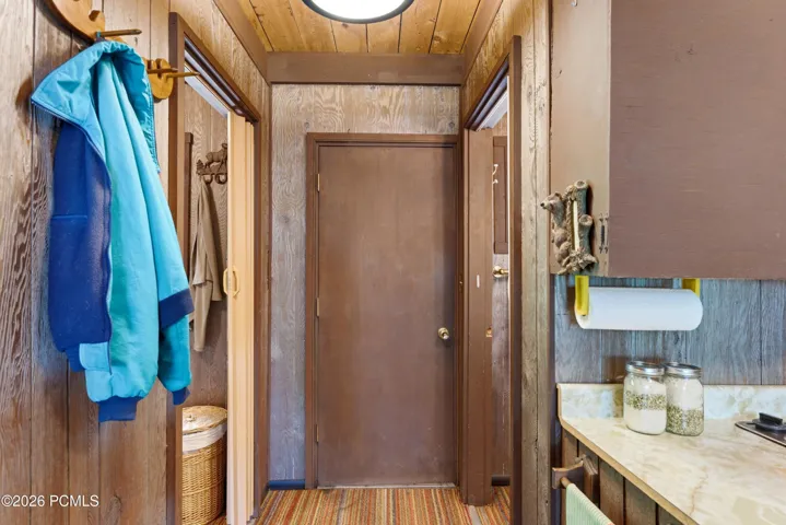 Cabin entry hallway and with coat hooks, wood paneling, and bathroom door in Timberlake, Utah