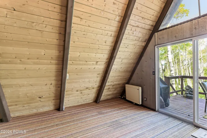 A-frame cabin with wood-plank flooring, sliding glass door to private deck, and views of surrounding aspen trees in Timberlake, Utah