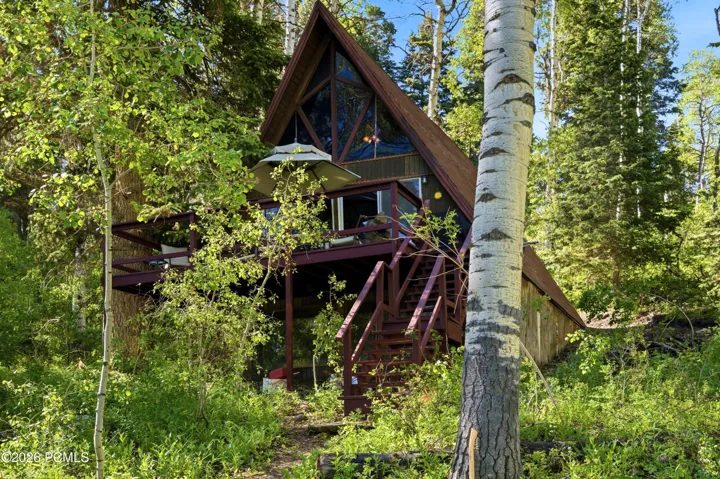 A-frame cabin exterior with multi-level deck and staircase surrounded by lush aspen and pine trees in Timberlake, Utah