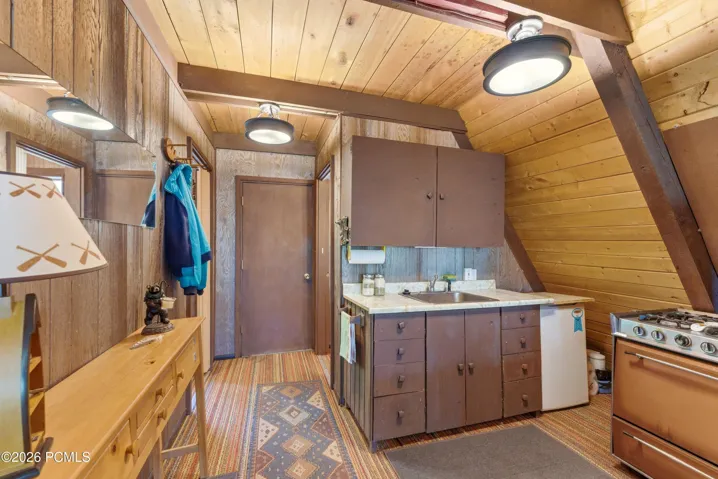 Cabin kitchen with wood cabinetry, range, refrigerator, and in an A-frame home in Timberlake, Utah