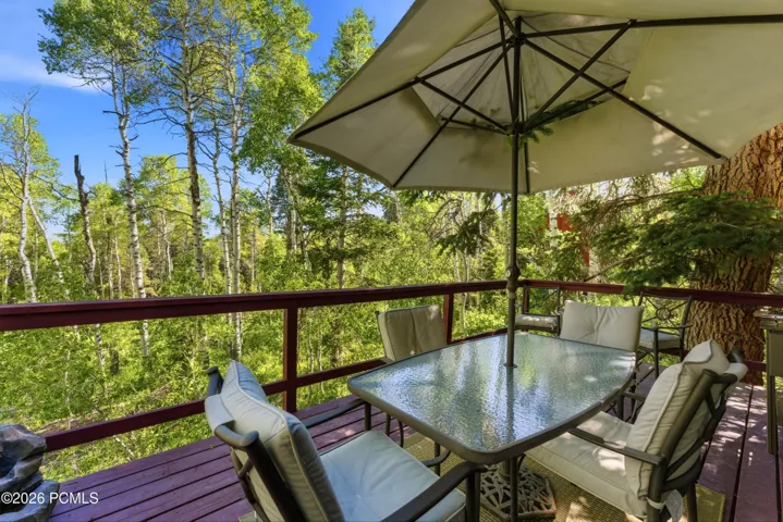 Spacious outdoor deck surrounded by mature trees, offering a private setting for dining, entertaining, or relaxing in the mountain air. Enjoy the peaceful wooded surroundings and natural beauty that make Timber Lakes a sought-after mountain community.