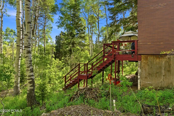 Exterior wood staircase leading up to cabin deck with aspens and pines in Timberlake, Utah