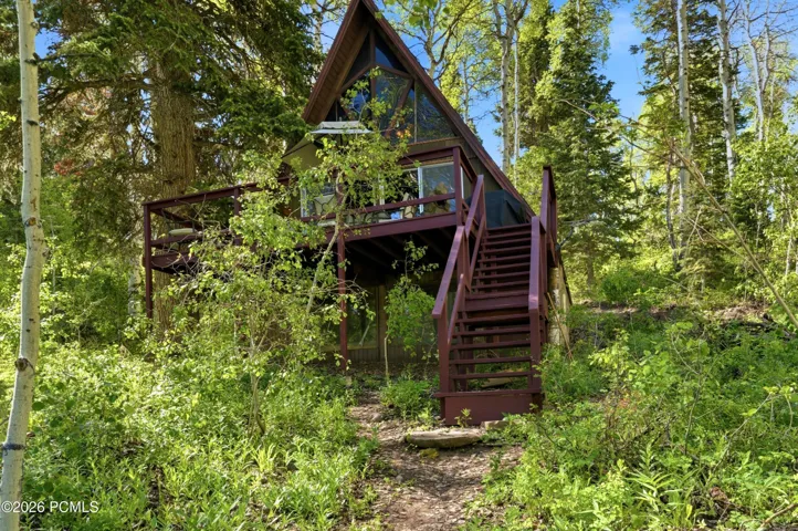 A-frame cabin exterior with staircase, deck, and surrounding pine forest in Timberlake, Utah