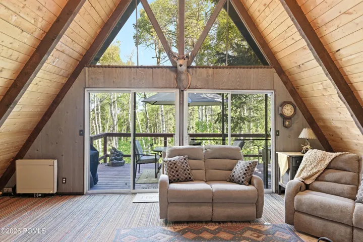 A-frame cabin living room with floor-to-ceiling windows, sofa, and natural light flooding through large glass panels in Timberlake, Utah