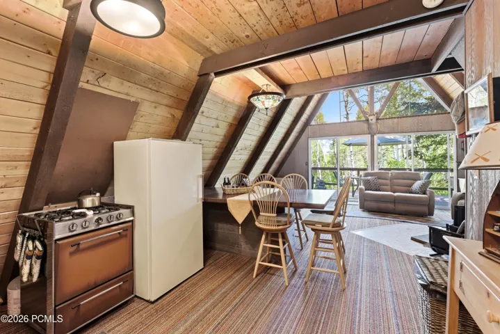 A-frame cabin kitchen and living room with gas range, refrigerator, dining table, and open view to living area in Timberlake, Utah