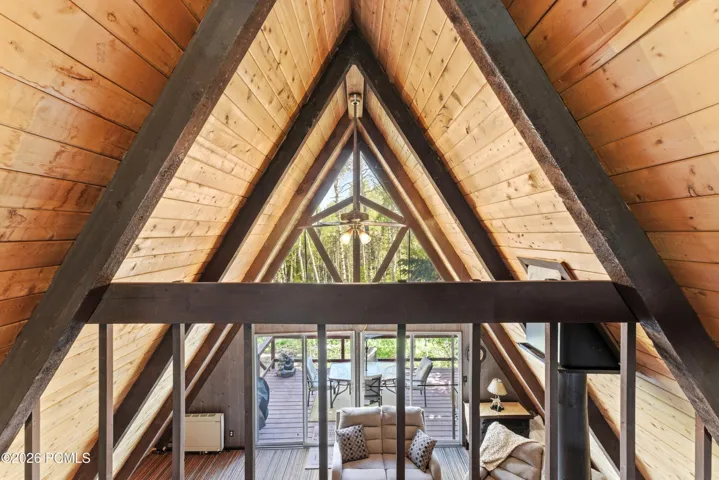 Interior A-frame peak view with dramatic triangular wood ceiling beams and large picture window overlooking trees in Timberlake, Utah
