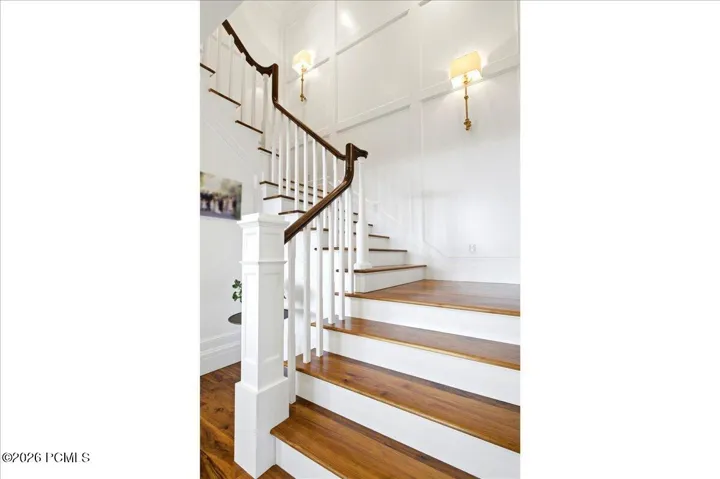 Hardwood staircase featuring white risers and balusters, and a dark wood-finish handrail