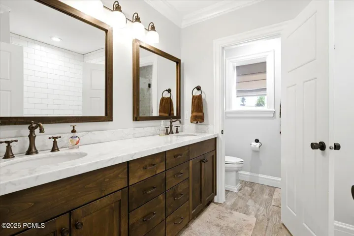 Dual wood-finish vanities with undermount sinks, bronze fixtures, and stone countertops