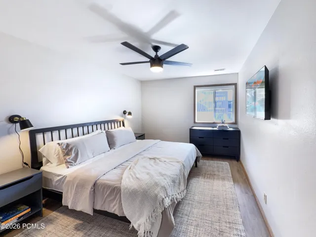 Primary bedroom with new window treatment, ceiling fan, furniture, TV and sconces