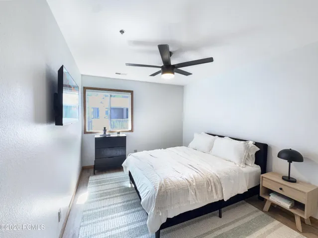 Second bedroom with new window treatment, ceiling fan, furniture and TV