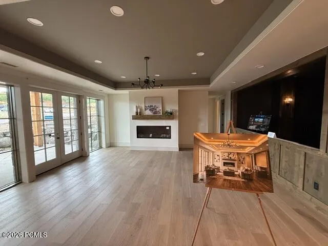 Spacious basement living space featuring a fireplace, tray ceiling, and French doors