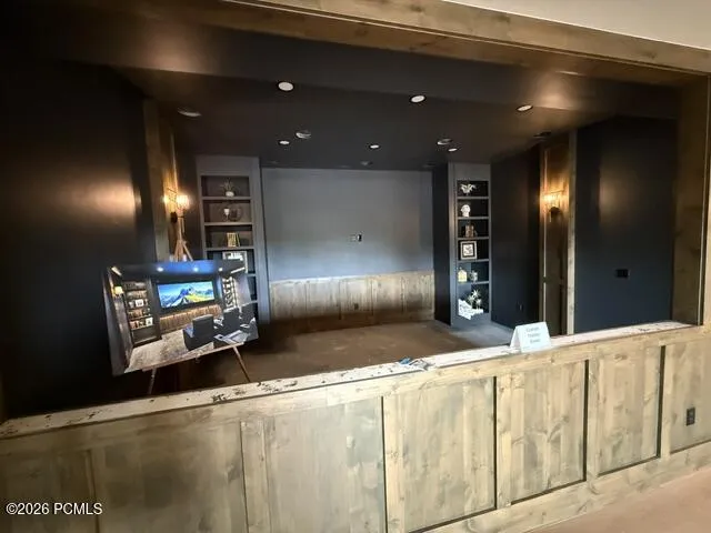 Theater room featuring built-in cabinetry with integrated shelving
