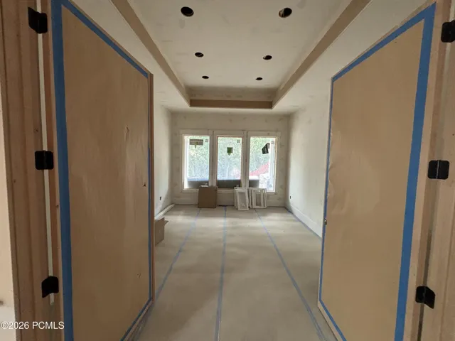 Office/library featuring a tray ceiling with recessed lighting, three large windows, and an expansive doorway