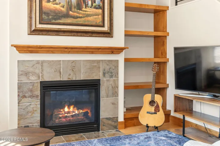 Custom gas fireplace with stone tile surround and built-in wood shelving — a standout feature in this move-in ready Park City townhome at Fox Point at Redstone.
