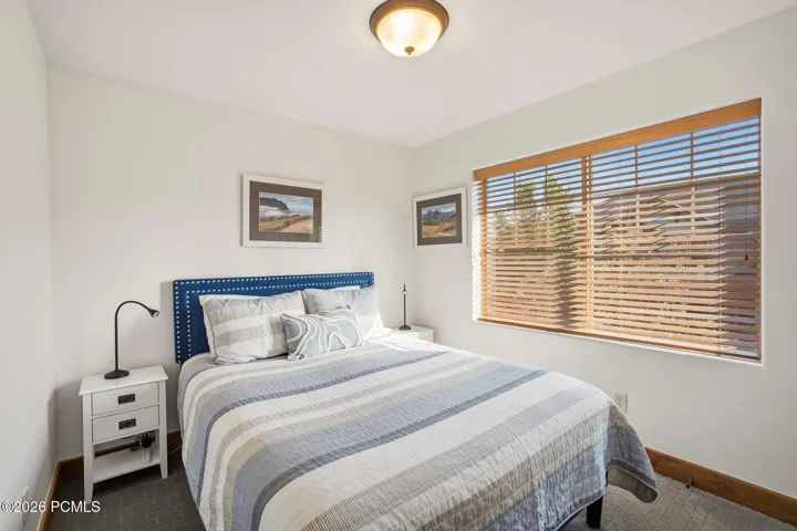 Second bedroom with carpet, large windows with blinds, and ample natural light — great for guests or a second occupant in this Park City townhome with nightly rental potential.