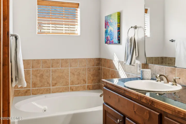 Primary bathroom jetted soaking tub with tile surround and wood vanity — spa-like amenities in the primary suite of this Park City townhome at 1603 W Redstone Ave.