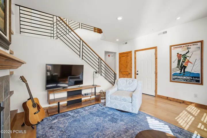 Spacious great room with open floor plan, hardwood floors, and staircase leading to loft/office — ideal layout for a Park City primary home, lock-and-leave, or investment property.