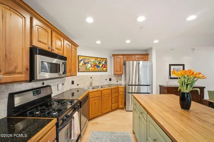 Upgraded kitchen with stainless steel appliances, gas range, and custom walnut-and-sage island — Park City townhome with ample cabinet storage and modern finishes.