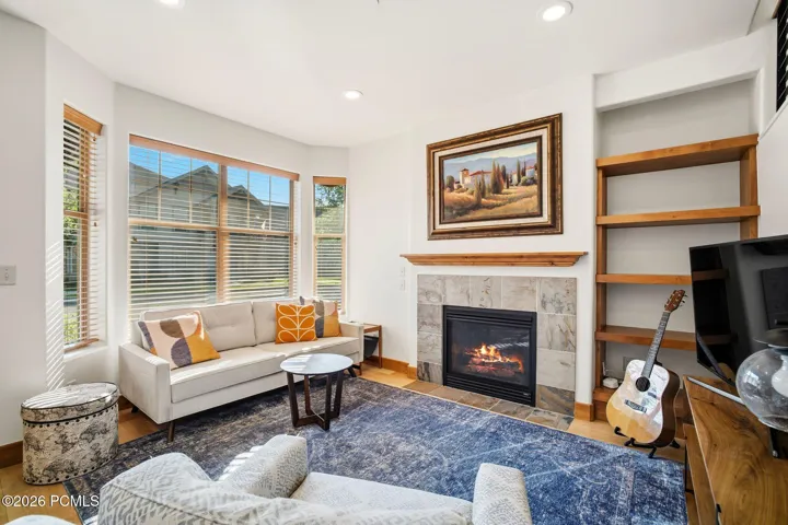 Sun-drenched great room with big windows, gas fireplace, and custom built-in shelving — Park City townhome with newer hardwood floors, fresh paint, and upgraded lighting throughout.