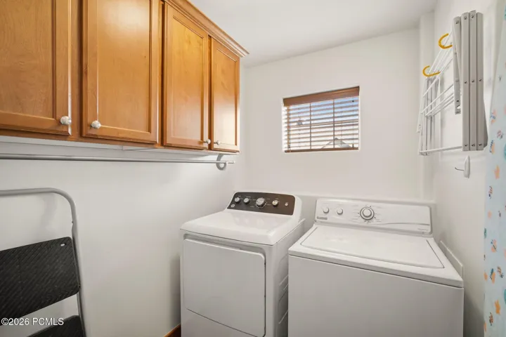 Dedicated laundry room with full-size washer and dryer, upper cabinet storage, and water softener — convenient in-unit laundry in this Park City townhome at Fox Point at Redstone.