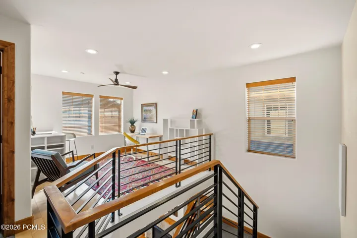 Upper level hallway with modern metal railing overlooking the two-story great room — dramatic open-concept design with newer carpet in this Fox Point at Redstone townhome.