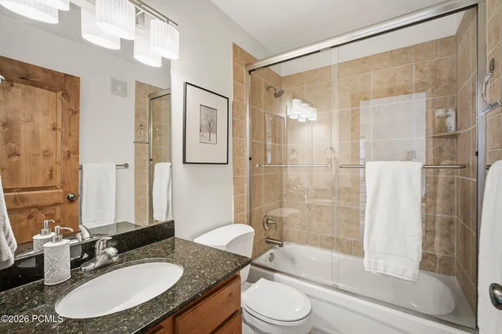 Full bathroom with tub/shower combo, tile surround, granite vanity, and updated fixtures — second full bath in this move-in ready Park City townhome at Fox Point at Redstone.