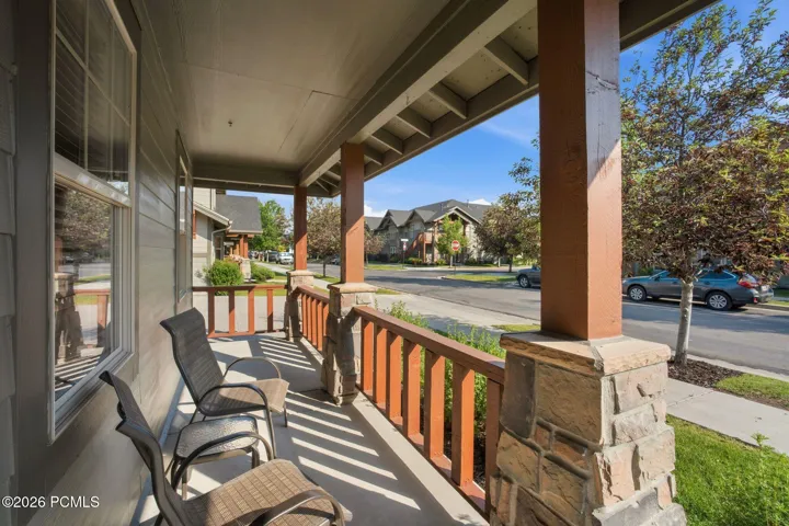 Covered front porch with stone columns and neighborhood views — welcoming entrance to this Park City townhome steps from restaurants and Redstone 8 Cinemas.